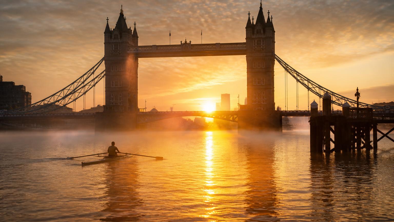 Sunrise over Tower Bridge with mist rising from the Thames and a lone rower